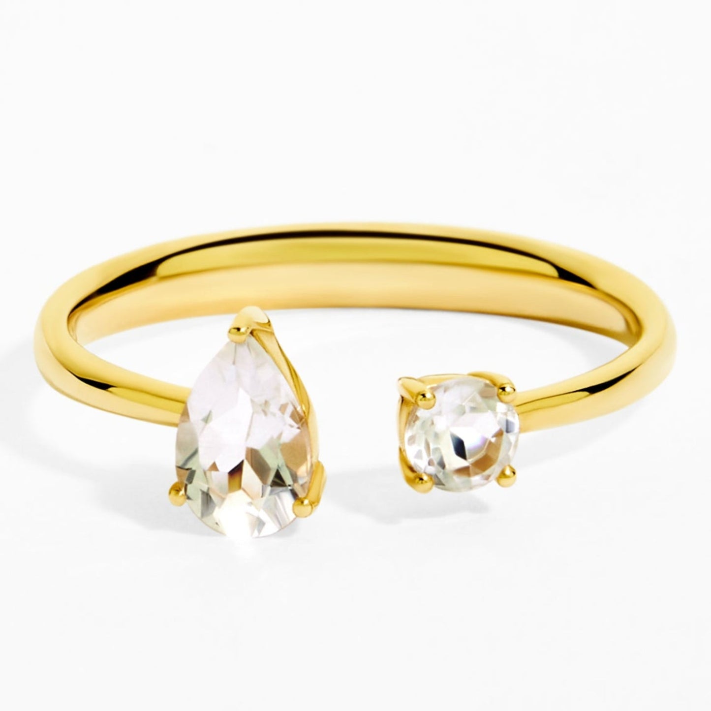 Gold ring with pear-shaped and round clear gemstones on a white background