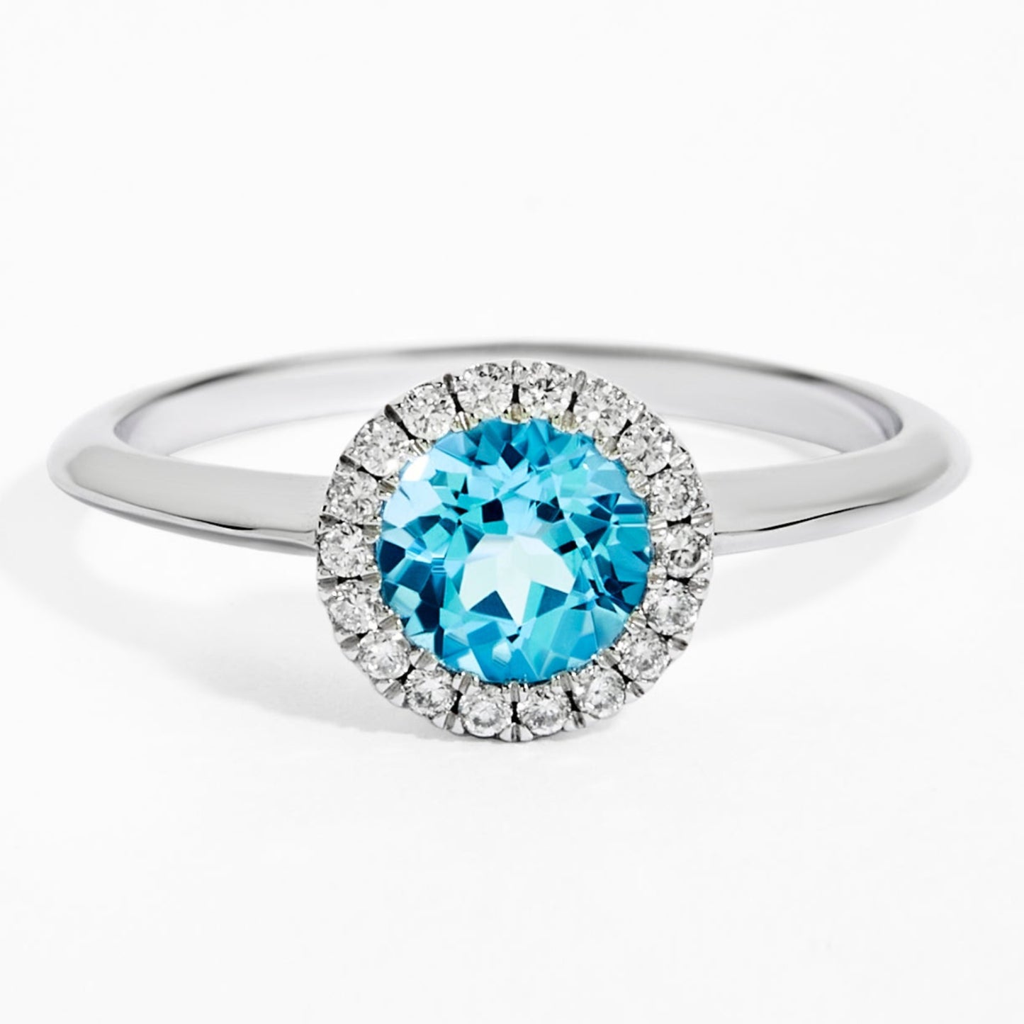 Ring with a blue gemstone and diamond halo on a white background