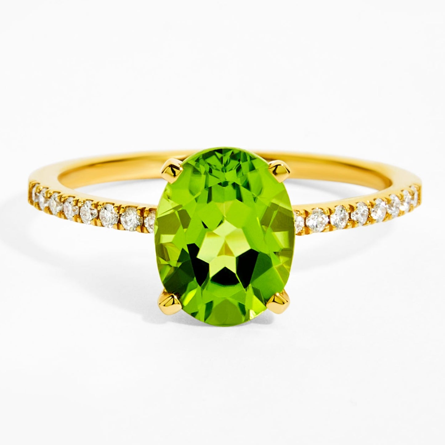 Gold ring with a green gemstone and diamond-studded band on a white background