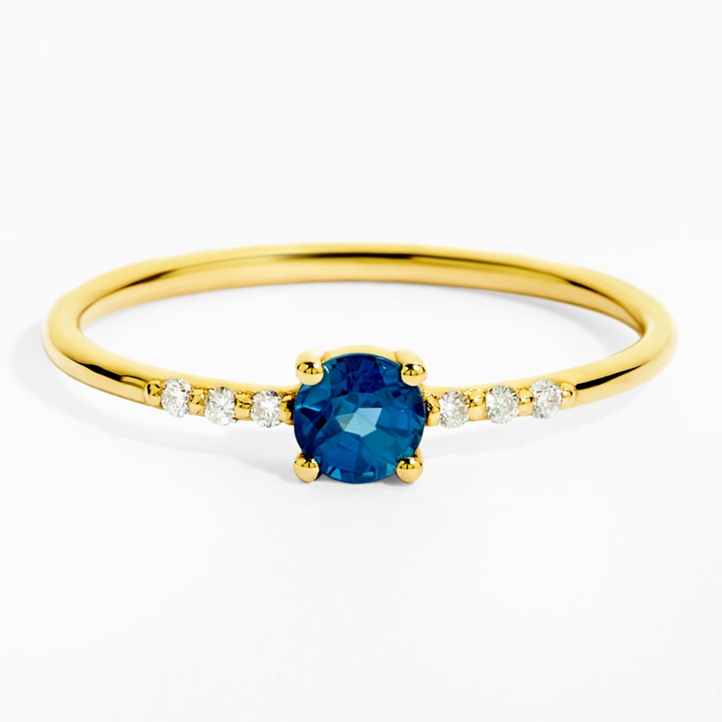 Gold ring with a blue gemstone and small diamonds on a white background