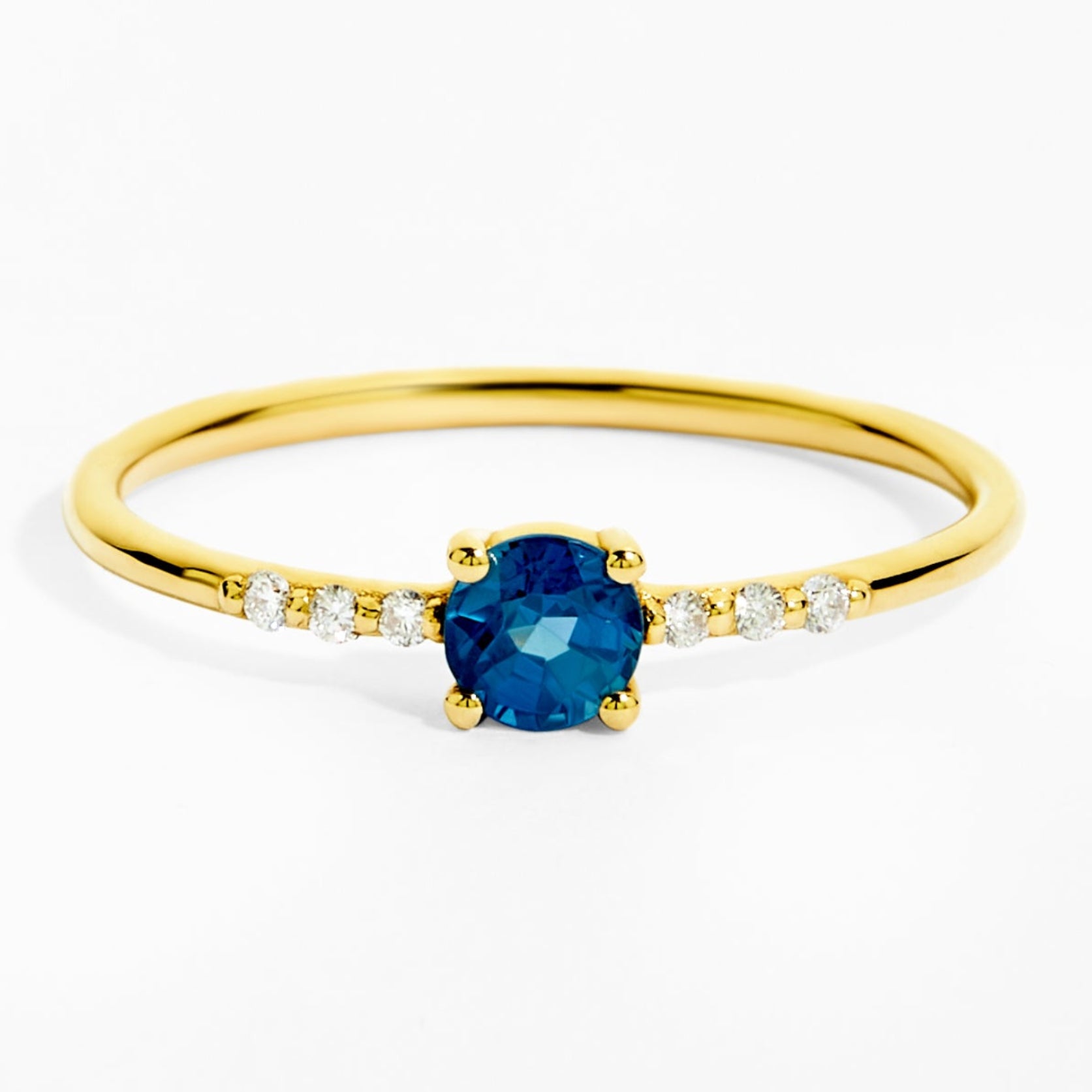Gold ring with a blue gemstone and small diamonds on a white background