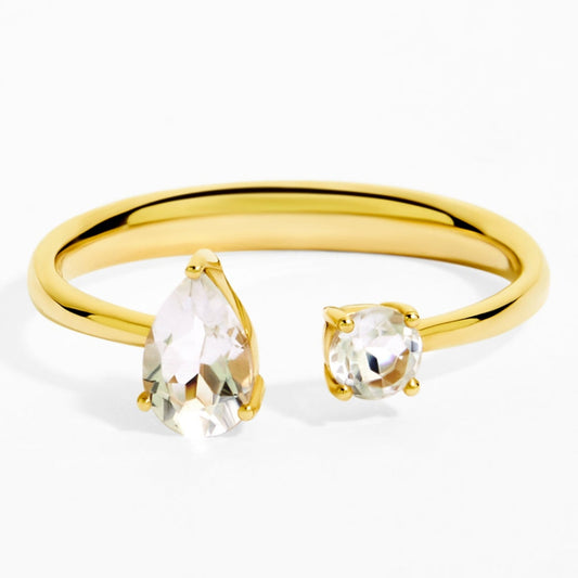 Gold ring with pear-shaped and round clear gemstones on a white background