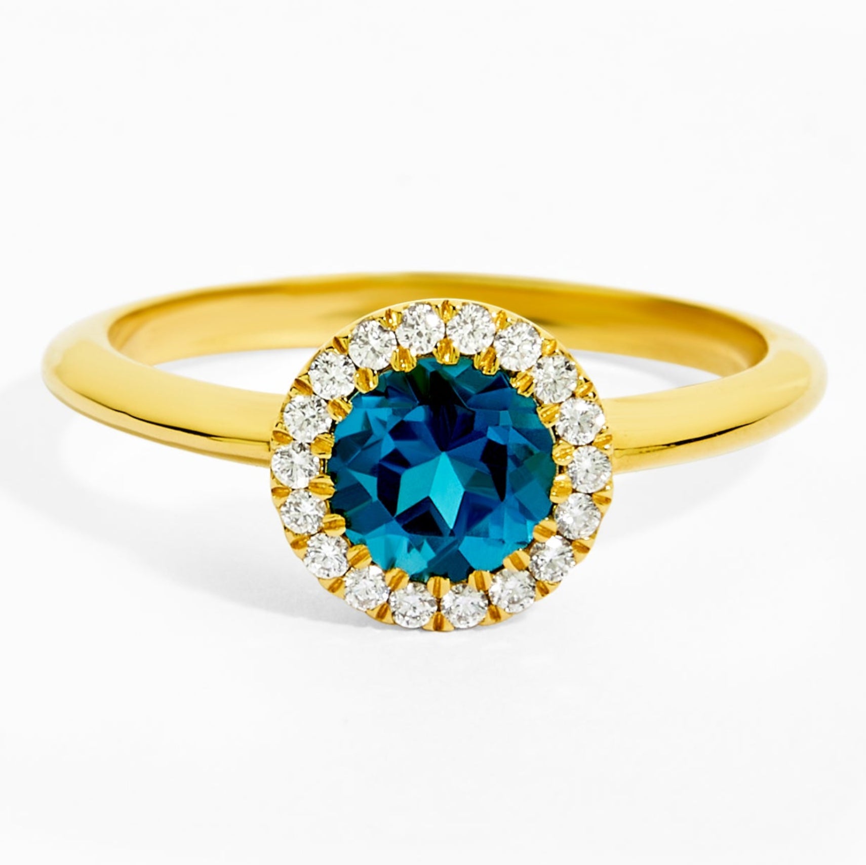 Gold ring with a blue gemstone and diamond accents on a white background