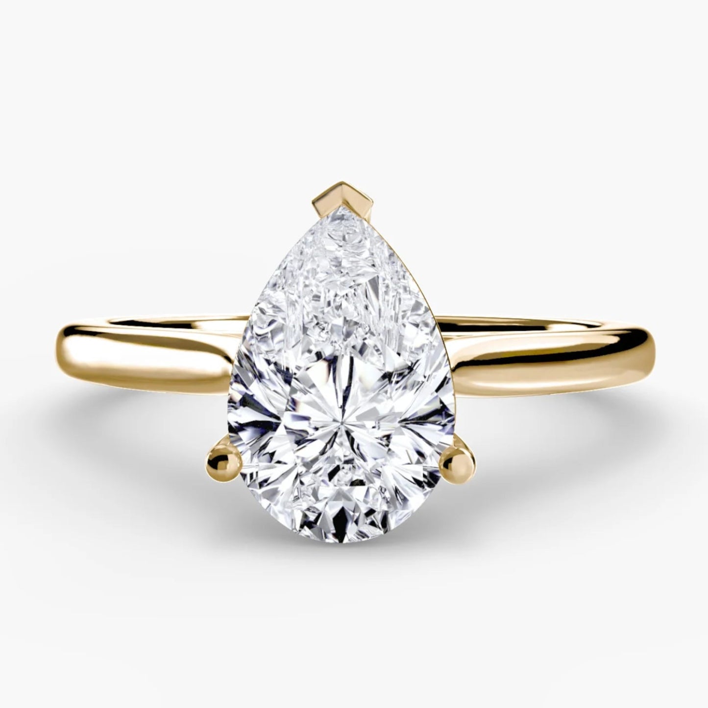 Gold ring with a pear-shaped diamond on a white background