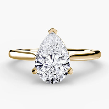 Gold ring with a pear-shaped diamond on a white background
