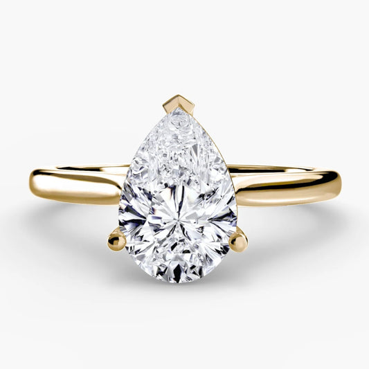 Gold ring with a pear-shaped diamond on a white background