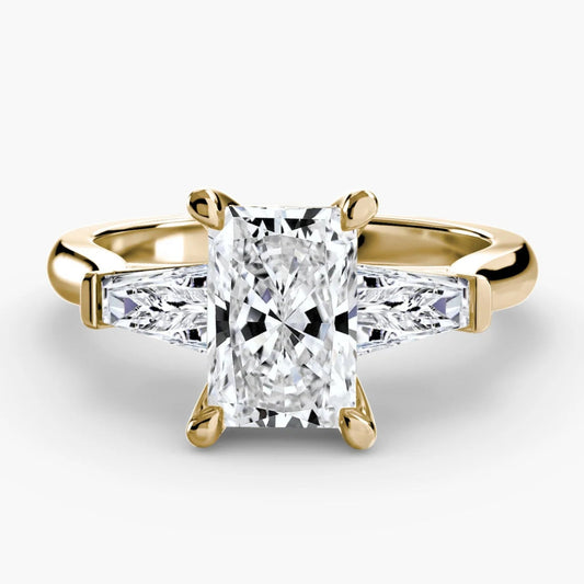 Gold ring with a large diamond and smaller diamonds on the sides against a white background
