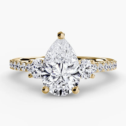 Gold ring with a pear-shaped diamond on a white background