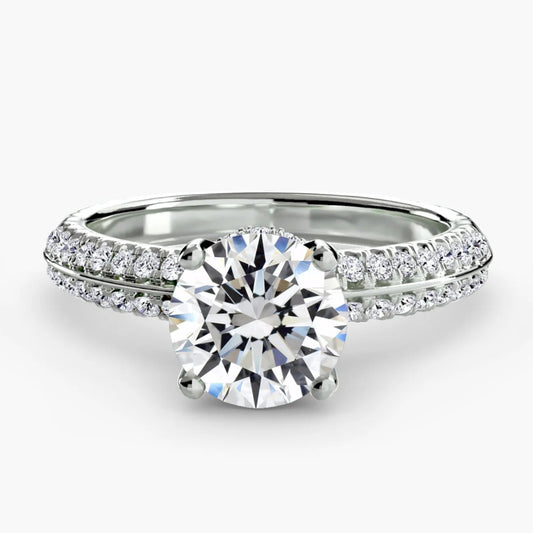 Silver ring with a large diamond and smaller diamonds on the band against a white background
