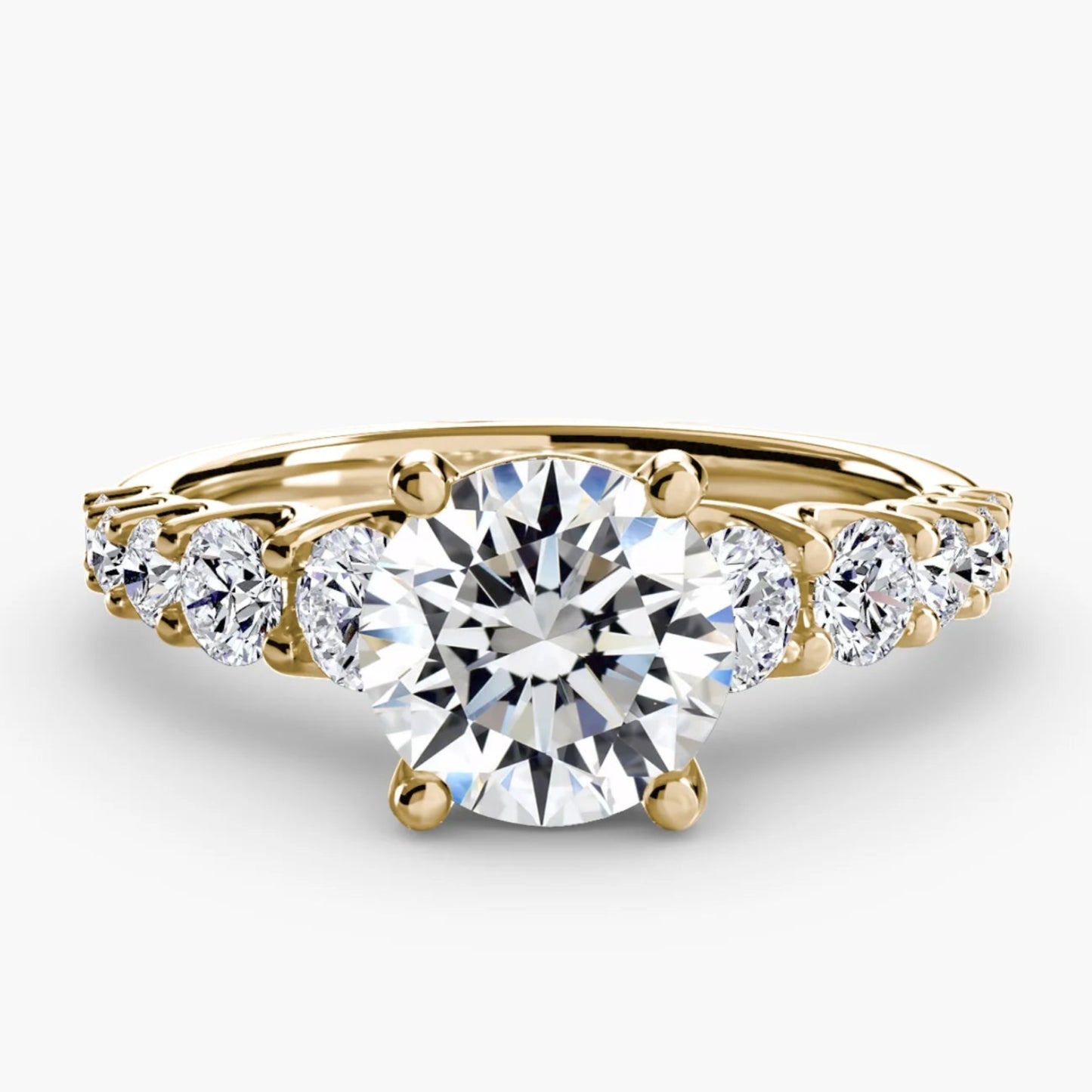 Gold ring with a large central diamond and smaller diamonds on the sides against a white background