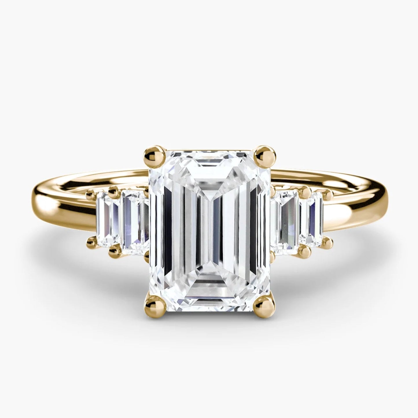 Gold ring with an emerald-cut diamond on a white background