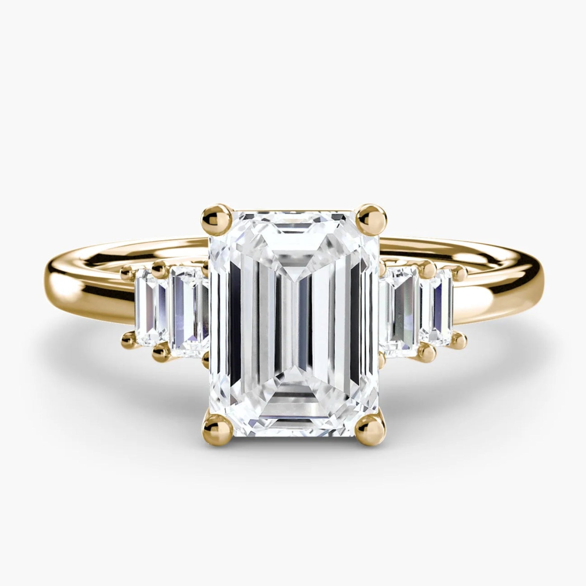 Gold ring with an emerald-cut diamond on a white background