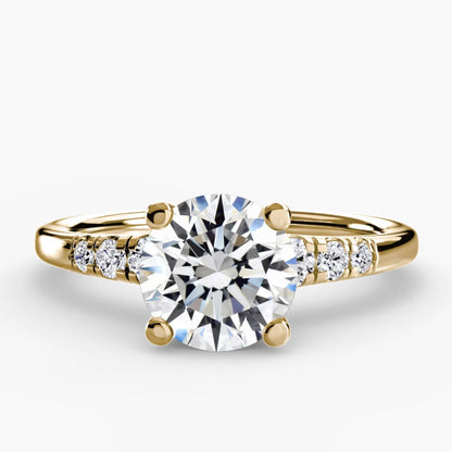 Gold ring with a large diamond and smaller diamonds on the band against a white background