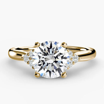 Gold ring with a large diamond and smaller diamonds on the band against a white background