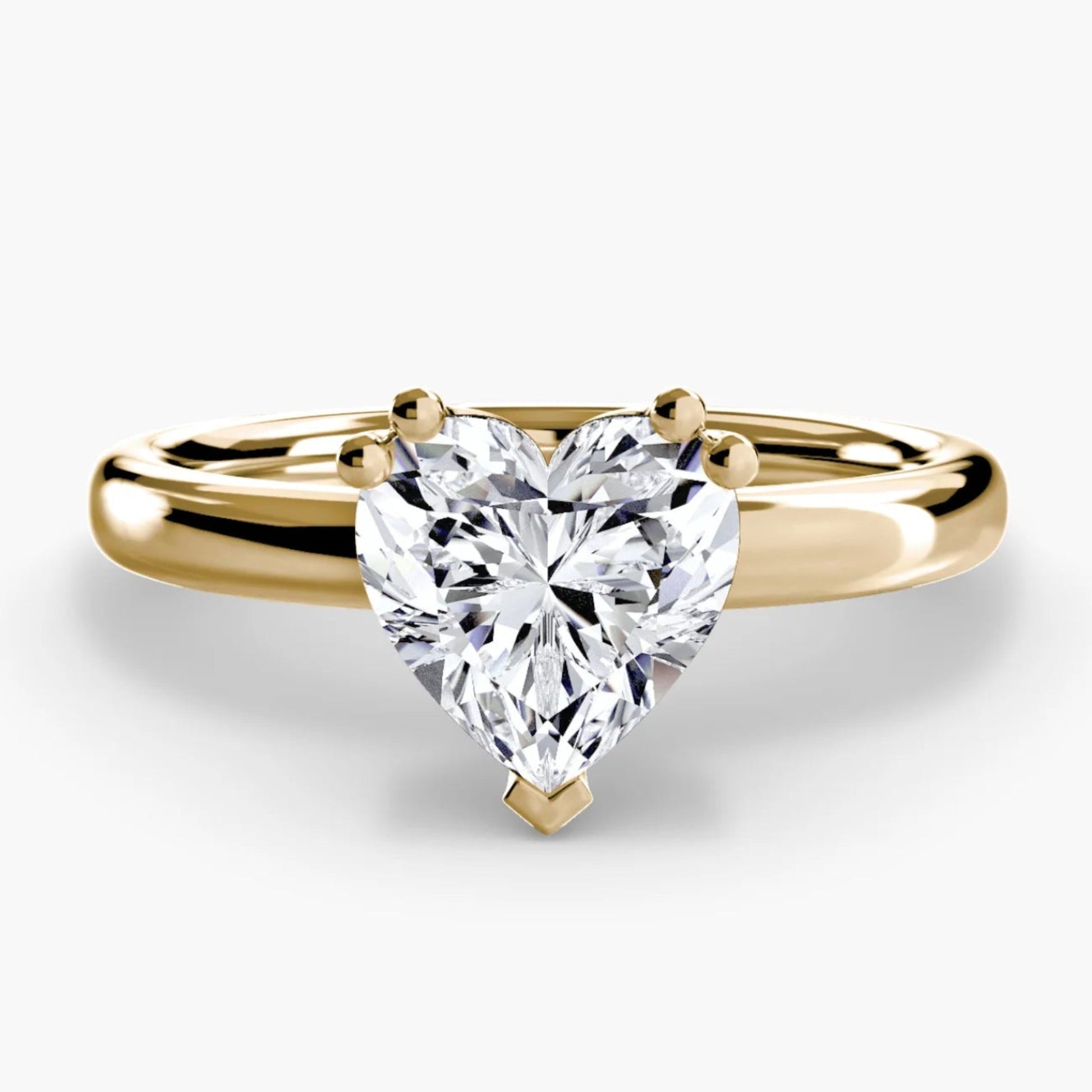 Gold ring with a heart-shaped diamond on a white background