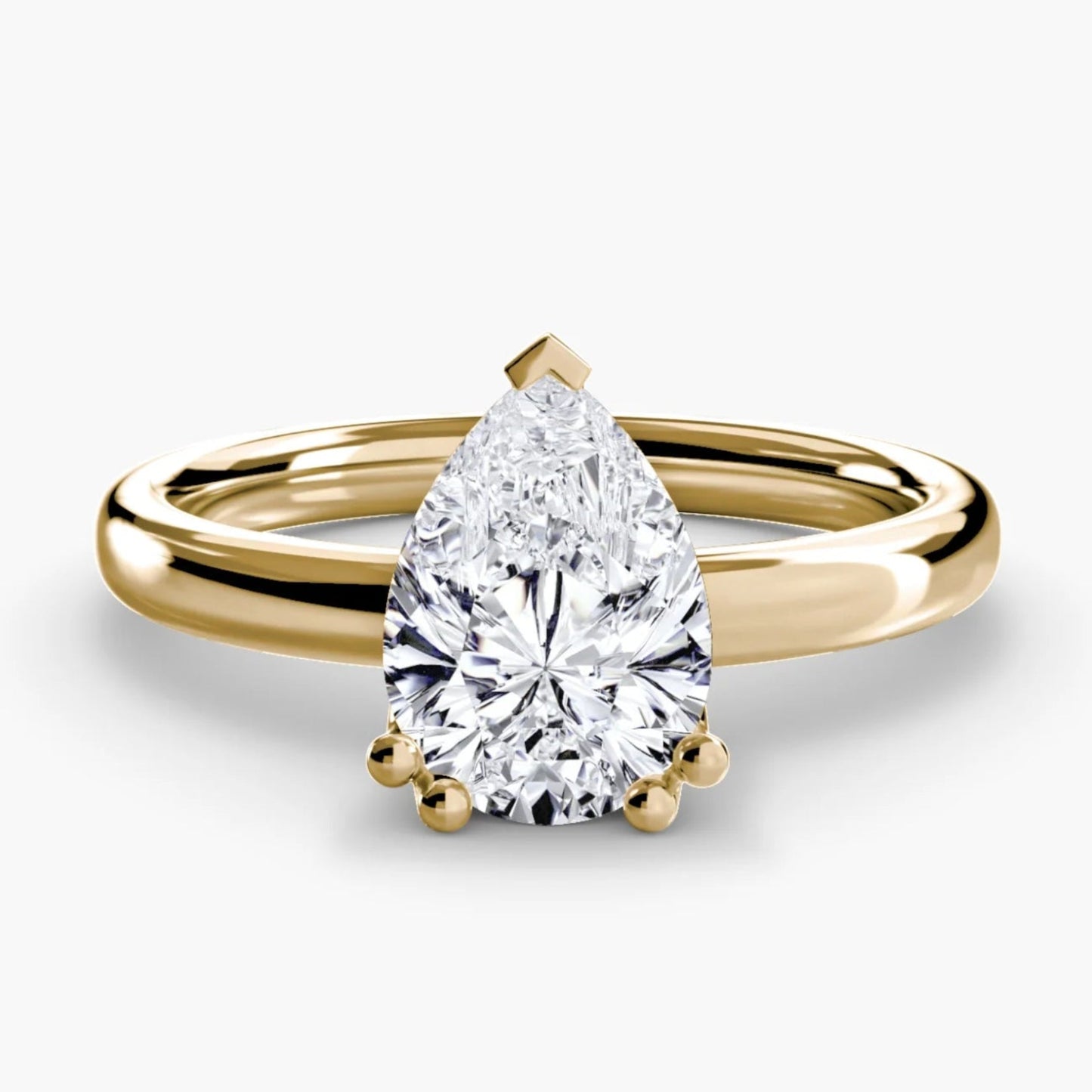 Gold ring with a pear-shaped diamond on a white background