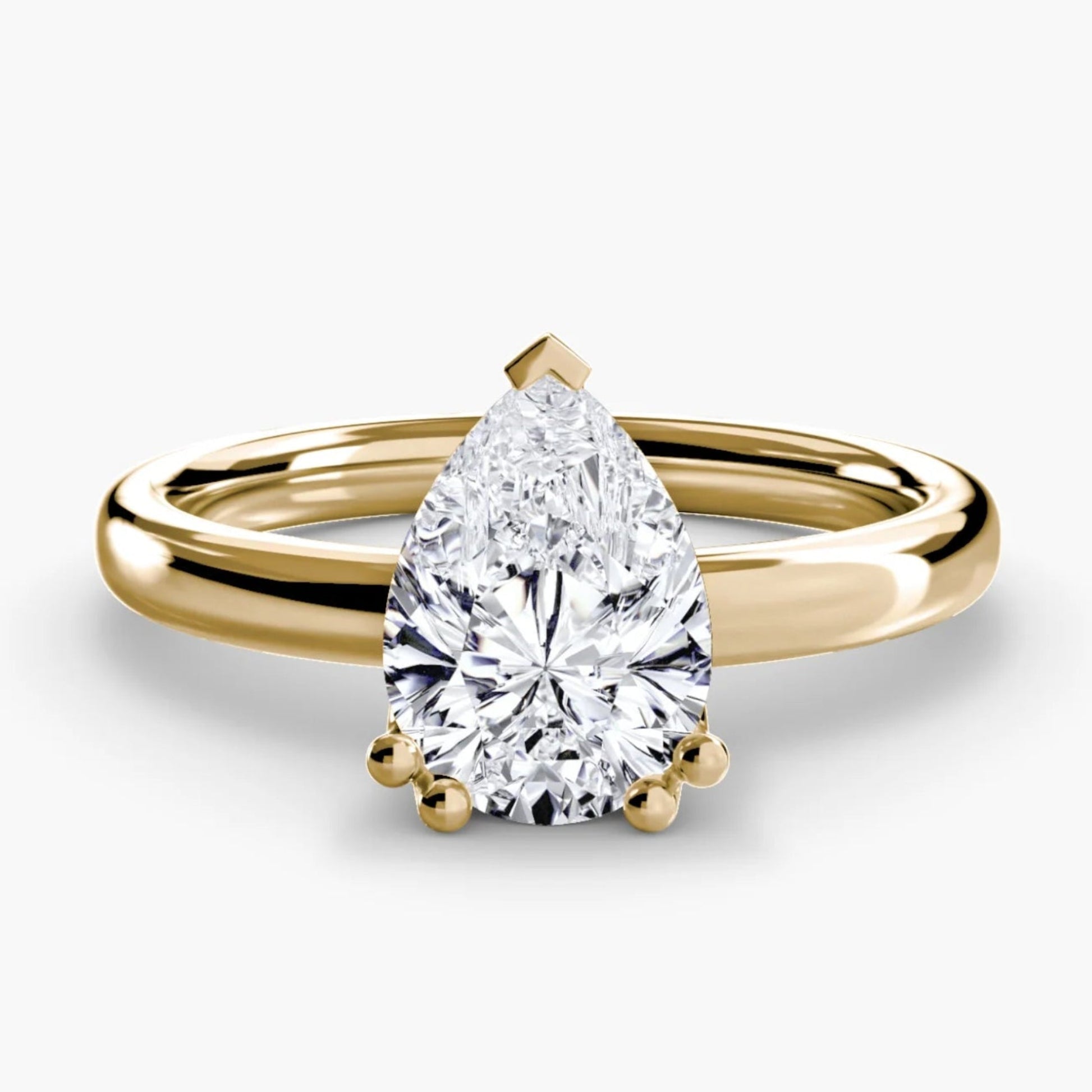 Gold ring with a pear-shaped diamond on a white background