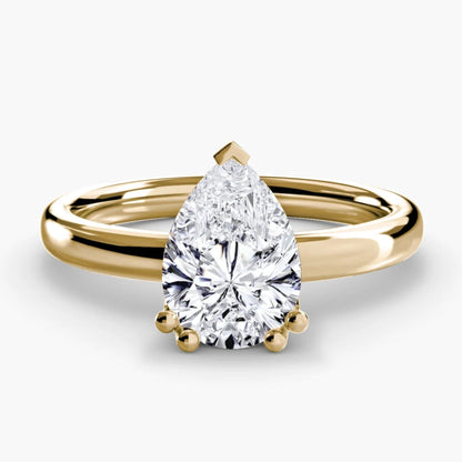Gold ring with a pear-shaped diamond on a white background
