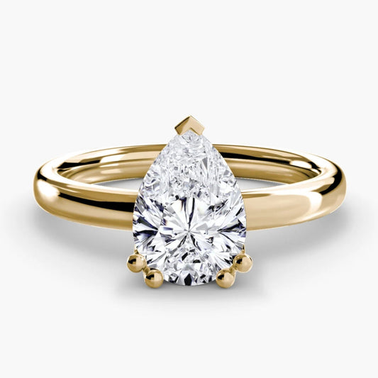Gold ring with a pear-shaped diamond on a white background